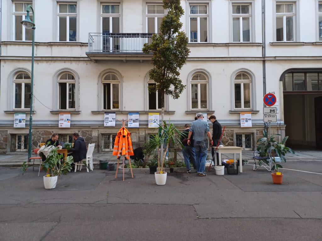 Das mellon Büro im Freien auf zwei Parkplätzen vor dem Haus: mit Tischen, Stühlen und Zimmerpflanzen zur Abgrenzung der Fahrbahn am Park(ing) Day