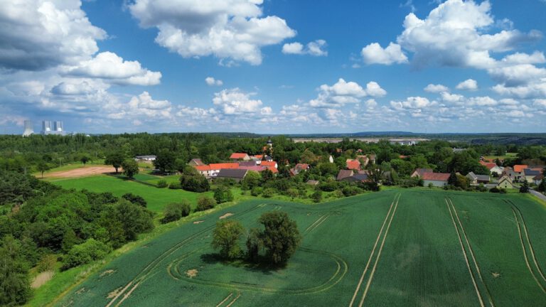 Foto: Eine kleine Gemeinde inmitten von landwirtschaftlichen Feldern, fotografiert aus der Vogelperspektive